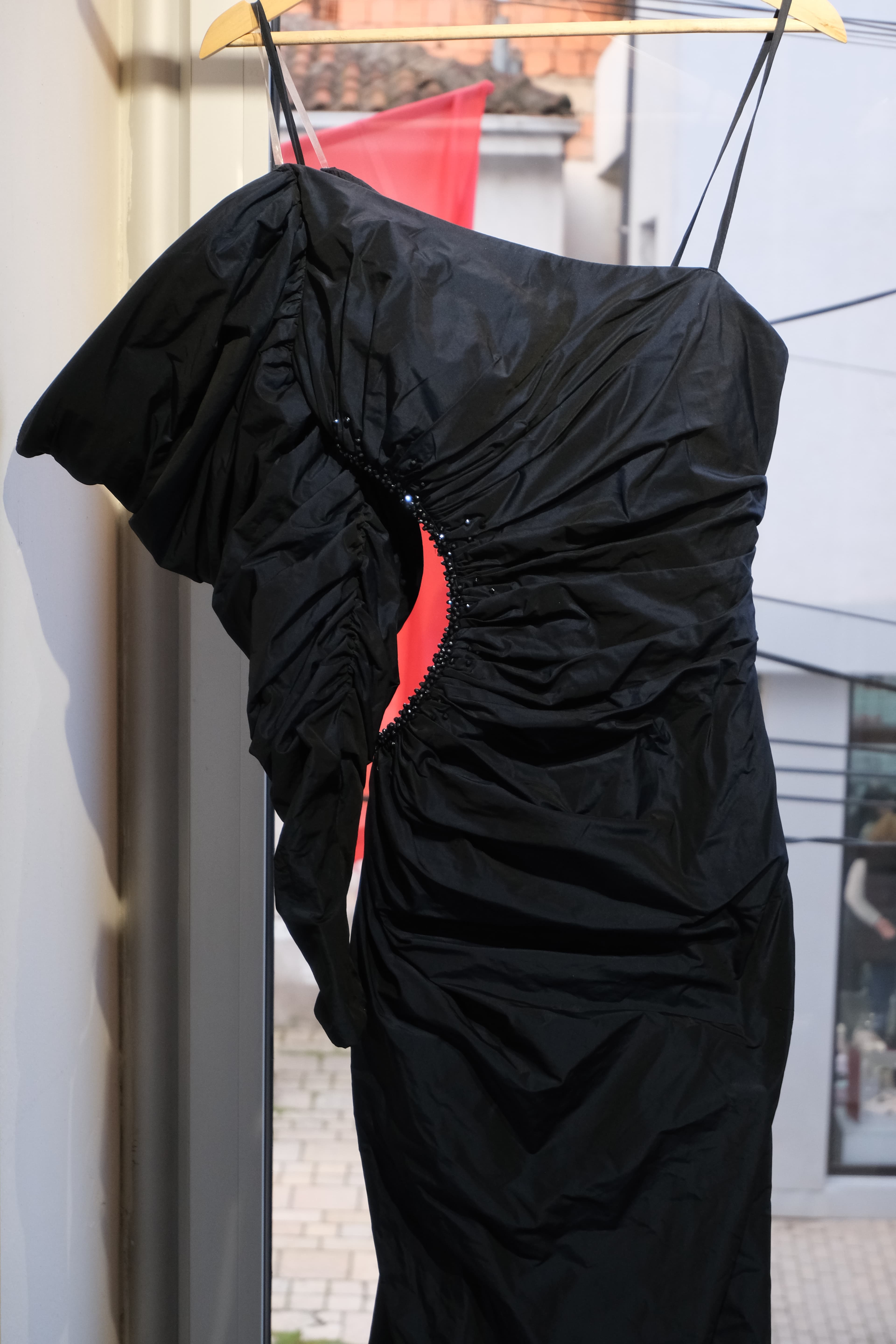 Close-up of a black gathered gown — ruched silk with hand-beaded neckline detail